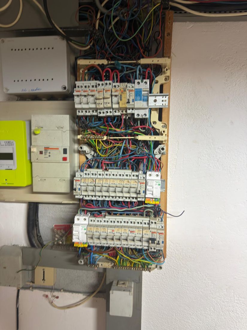 Ancien tableau électrique vétuste sur planche bois avant remplacement en Haute-Savoie